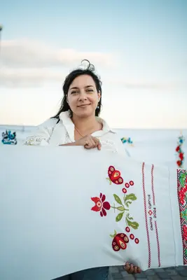 Учасниця з полотном, вишитим червоними квітами